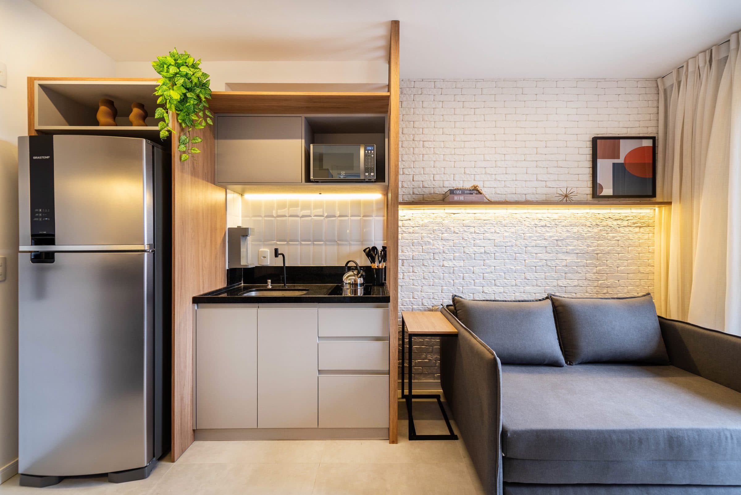Studio com cozinha planejada, marcenaria em madeira e sofá-cama